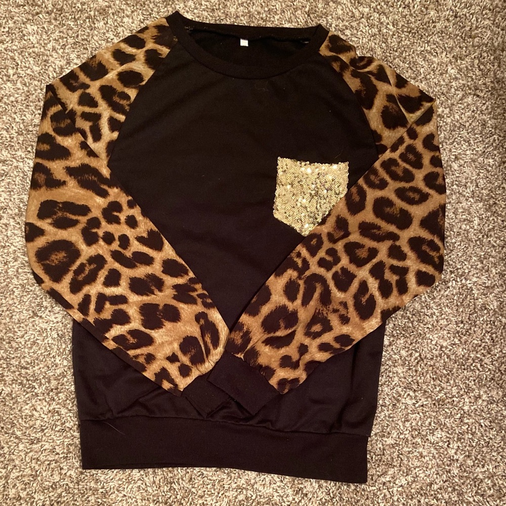 Black long sleeved top with leopard print sleeves and gold sequin pocket.
